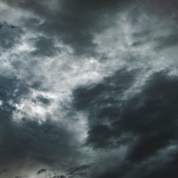 Dunkle Gewitterwolken bedecken den Himmel und schaffen eine stimmungsvolle und dramatische Atmosphäre mit verschiedenen Grautönen und dezentem Licht, das an einigen Stellen durchscheint.