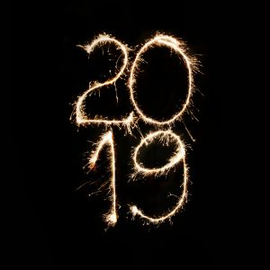 Die Zahlen 2019 werden mit Wunderkerzen vor schwarzem Hintergrund in die Luft geschrieben, wodurch ein heller, leuchtender Effekt entsteht, der in der Dunkelheit auffällt.