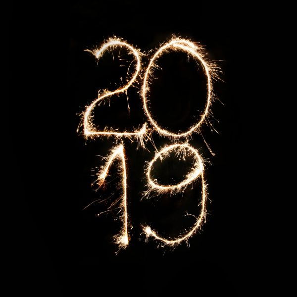 Die Zahlen 2019 werden mit Wunderkerzen vor schwarzem Hintergrund in die Luft geschrieben, wodurch ein heller, leuchtender Effekt entsteht, der in der Dunkelheit auffällt.