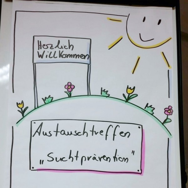 Handgezeichnetes Plakat mit Blumen, Gras, einer Sonne und zwei Schildern. Auf dem einen steht "Herzlich Willkommen" und auf dem anderen "Austauschtreffen Suchtprävention".