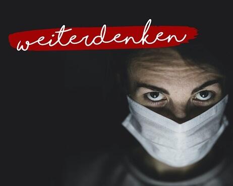 Eine Person mit einer weißen Gesichtsmaske blickt vor einem dunklen Hintergrund direkt in die Kamera. Das Wort "Weiterdenken" ist in roter Schrift über dem Bild zu lesen.