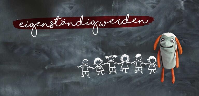 Eine Puppe mit orangefarbenen Ohren und grauem Körper steht neben Kreidezeichnungen von fünf Kindern, die sich an einer Tafel an den Händen halten. Darüber steht in weißer Schrift auf einem roten Pinselstrich das deutsche Wort eigenständigwerden.