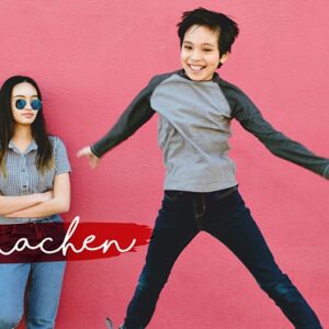 Zwei Kinder stehen vor einer rosafarbenen Wand; eines springt energisch, während das andere, das eine Sonnenbrille trägt, mit verschränkten Armen dasteht. Unten links steht der Text "fit machen".