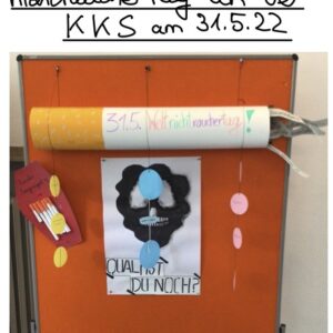 Eine Pinnwand mit deutschem Text zum Weltnichtrauchertag am 31. Mai 2022. Es zeigt eine große Modellzigarette, Papierlungen und ein Plakat mit der Frage "Qual ist du noch?", umgeben von bunten Dekorationen.