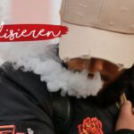 Eine Person mit beiger Mütze atmet Dampf aus, während sie nach unten schaut. Sie trägt eine schwarze Jacke mit einem roten Rosenaufnäher. Das Wort sensibilisieren ist in weißer Schrift auf einem roten Pinselstrich quer über das Bild geschrieben.