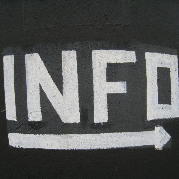 Weißer, gemalter Text INFO mit einem nach rechts zeigenden Pfeil, dargestellt auf schwarzem Hintergrund.