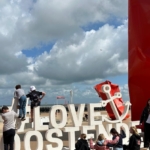 Die Kinder und Jugendlichen klettern auf einem "Love Ostende"-Schild am Strand.